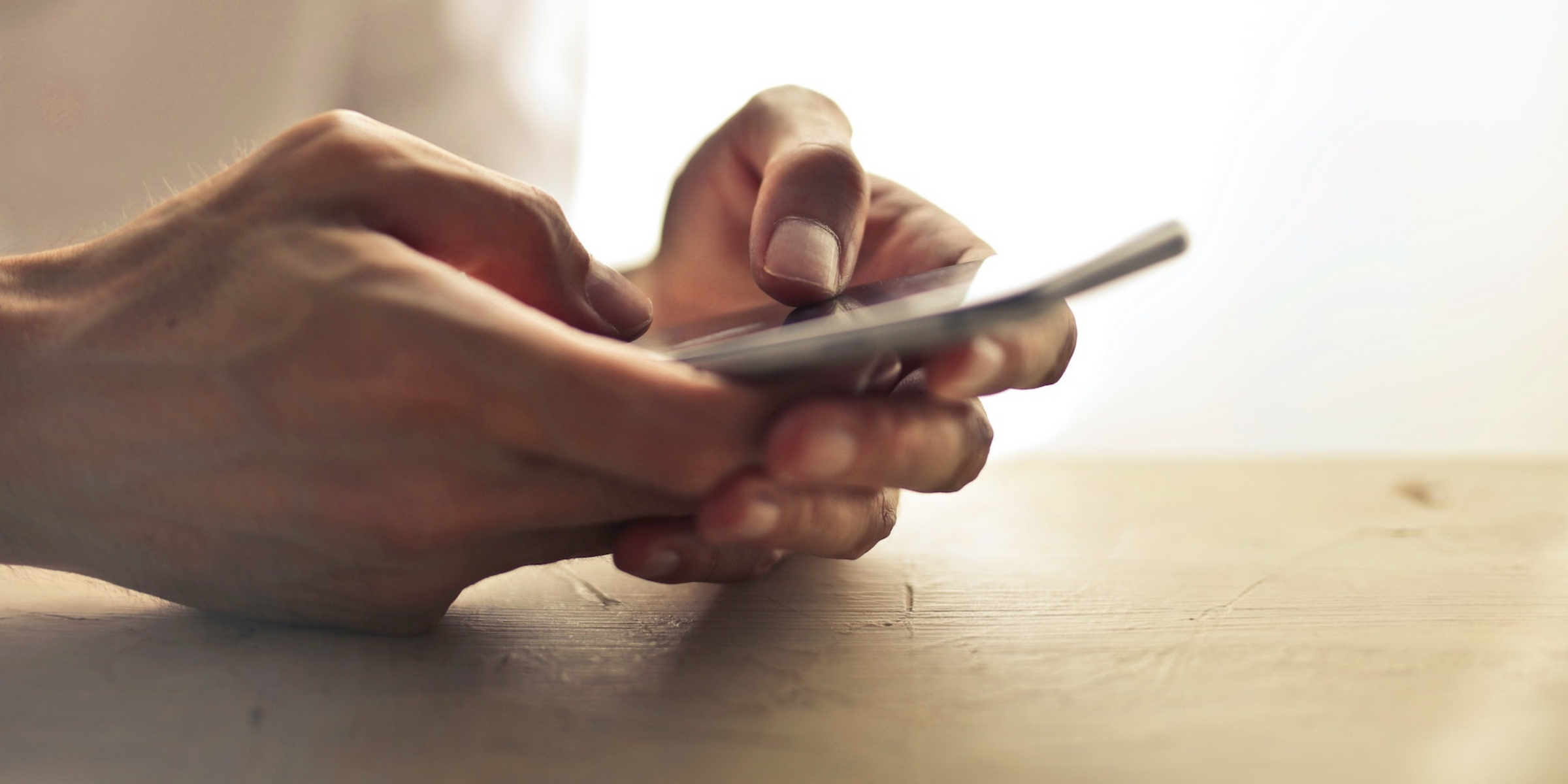 Hands typing on a mobile device, initiating an automation for healthcare.