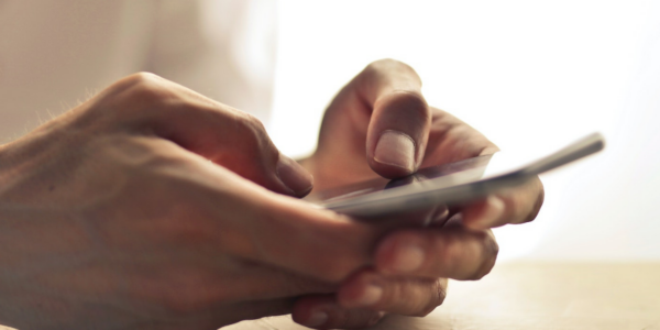 Hands typing on a mobile device, initiating an automation for healthcare.