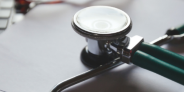 A stethoscope laying on a laptop keyboard, a representation of how healthcare and technology can supplement and improve each other.