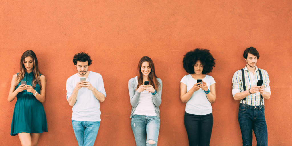 Five patients standing in front of a wall, all texting on their cell phone