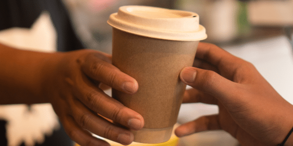 barista hands a to go coffee to customer