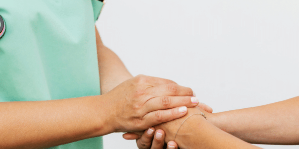 A doctor expresses empathy to a patient by holding their hand.