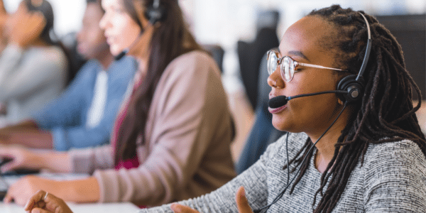 a row of call center employees talk in head sets.