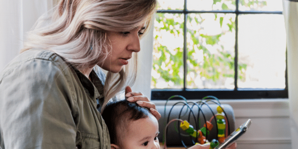 woman with sick child calls doctor's office on a smart phone