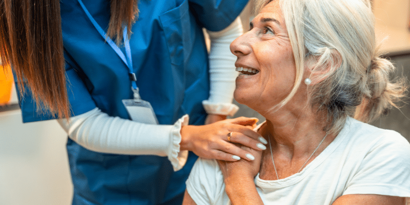 A healthcare worker comforts a patient in a white t-shirt.