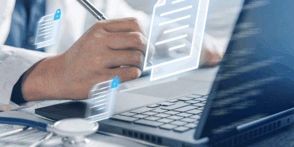 A doctor using AI types on a laptop and takes notes